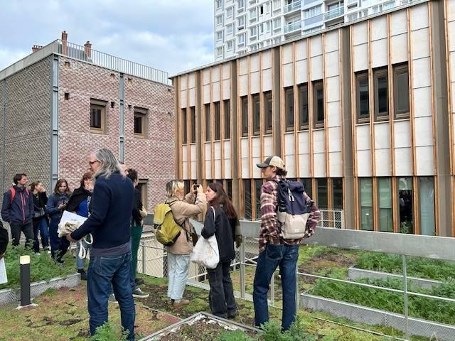 Depuis les toits dédiés aux Pariculteurs, vue du volume auditorium habillé des pavés de l’ancien parvis et de l’extension en bois avec sa pierre claire de réemploi également. photo H. Michelson